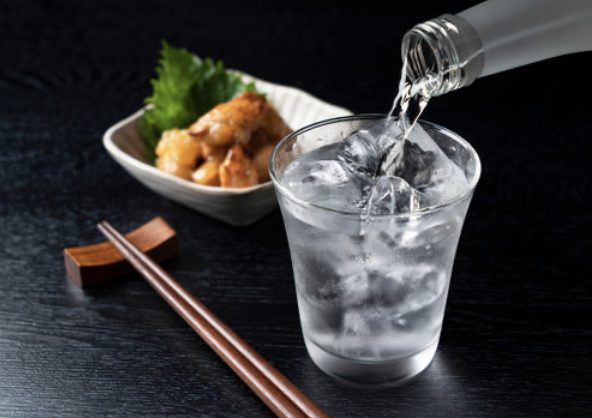 焼酎のロック。グラスの氷に球磨焼酎を注ぐ様子と、肴の小鉢